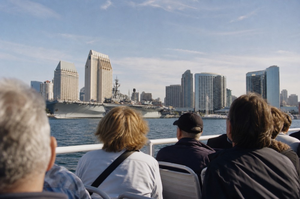 A narrated sightseeing boat passing San Diego's waterfront landmarks, late-morning light