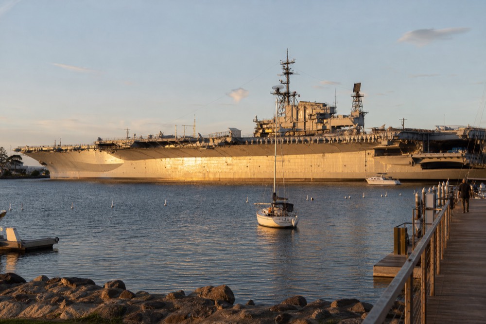 The massive gray aircraft carrier museum ship on the San Diego waterfront at golden hour, long shadows and warm low light