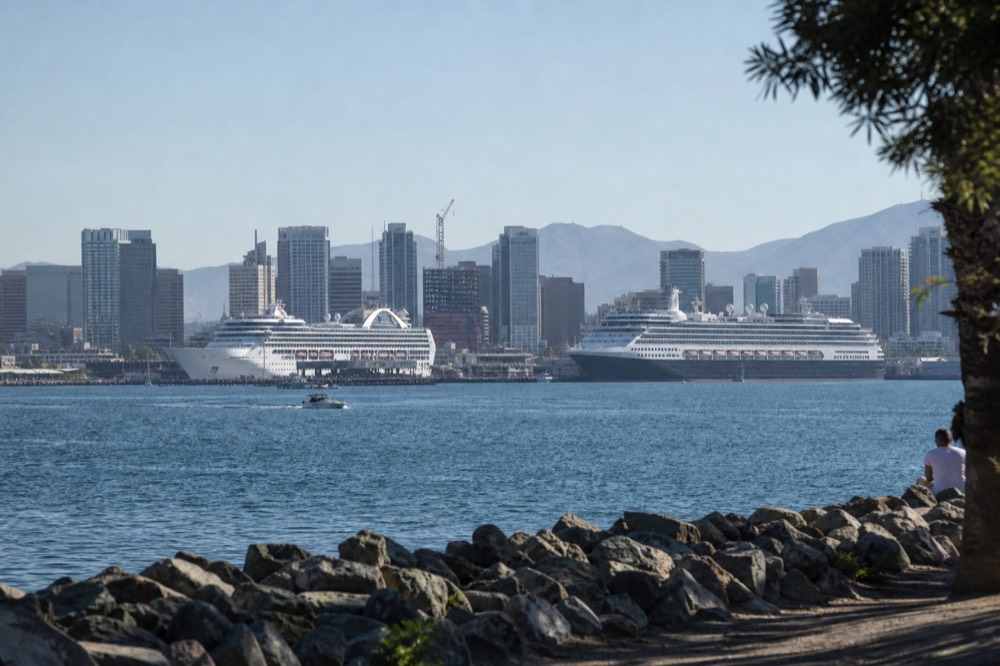 Two cruise ships berthed along the downtown San Diego waterfront seen from across the bay on a clear morning