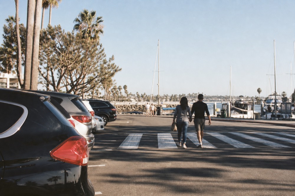 Crosswalk leading from the Broadway Pier parking row toward the San Diego cruise docks under palm shadows