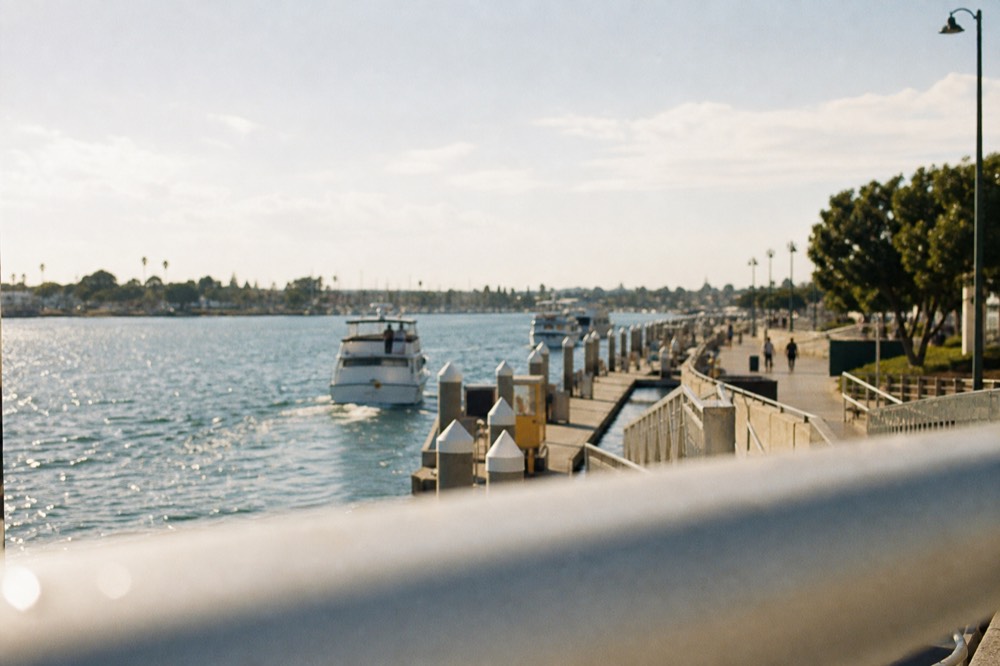 San Diego's boat departure docks and waterfront promenade, a railing or shoulder softly out of focus in the foreground