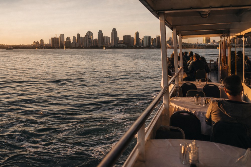 An evening dinner cruise ship on San Diego Bay at golden hour, long shadows and warm low light