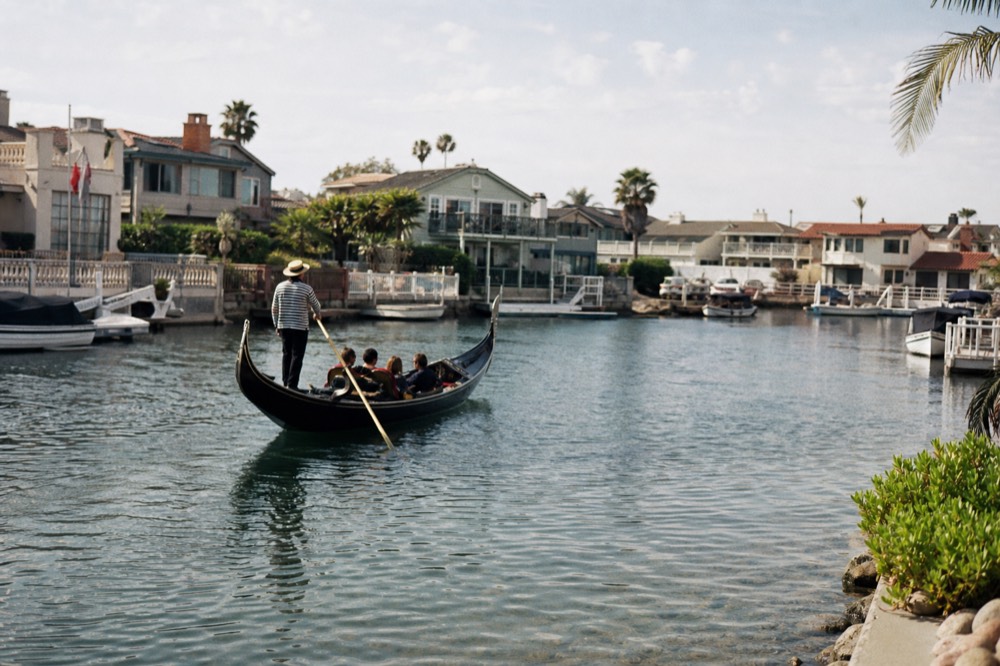 A black Venetian gondola in the calm canals of the Coronado Cays, late-morning light