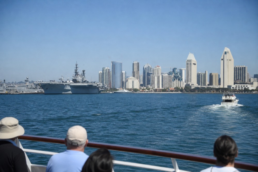 The San Diego harbor cruise route with bay water, gray naval ships and the city skyline, late-morning light