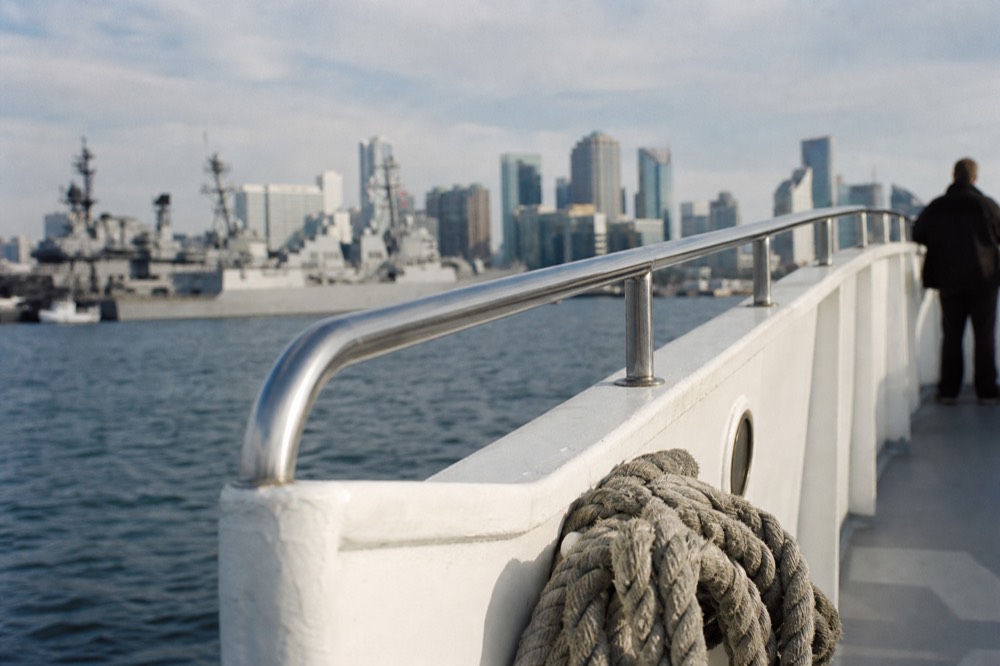 The San Diego harbor cruise route with bay water, gray naval ships and the city skyline, shallow depth of field, textures sharp