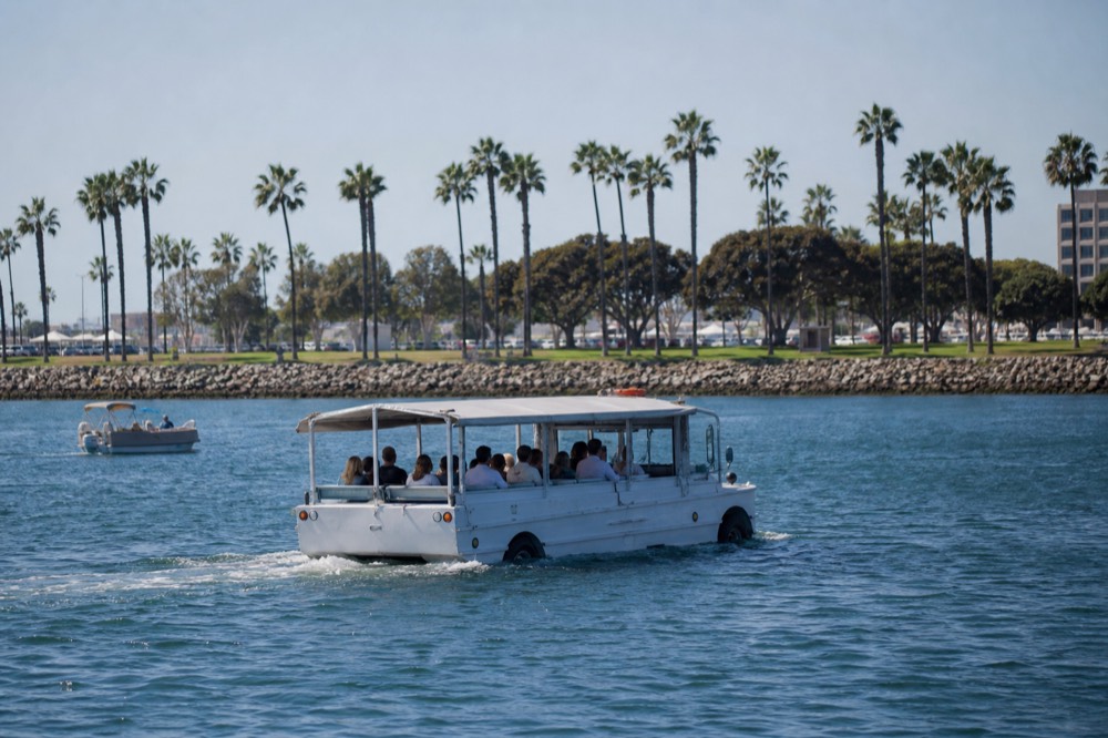 A boxy amphibious sightseeing vehicle around San Diego's palm-lined waterfront, late-morning light