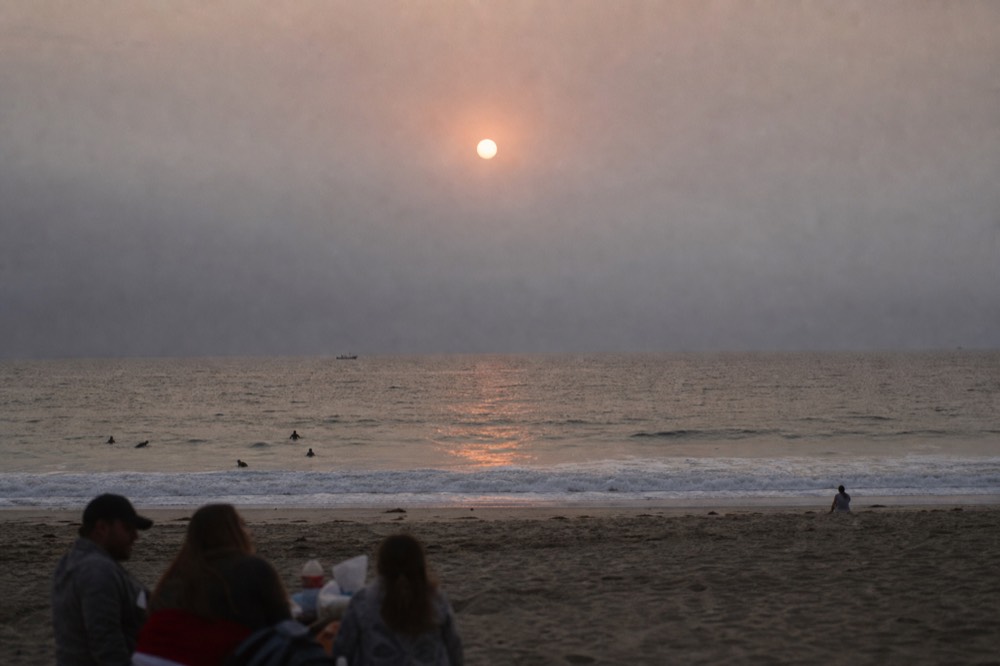 The marine layer standing as a grey wall across the horizon at sunset in San Diego, the sun reduced to a pale disc above the water