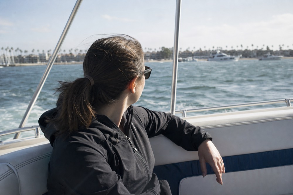 A windbreaker and sunglasses left on a boat bench with choppy San Diego Bay water behind on a bright, cool day