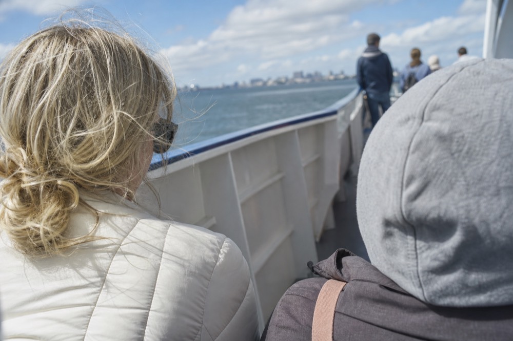 Passengers dressed in layers for wind and sun on a San Diego boat deck, shallow depth of field, textures sharp